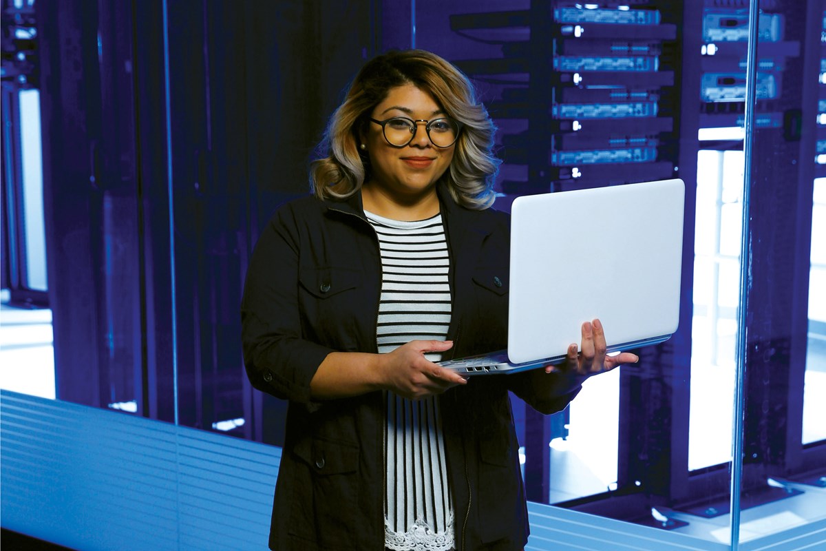 Woman in computer lab holding laptop